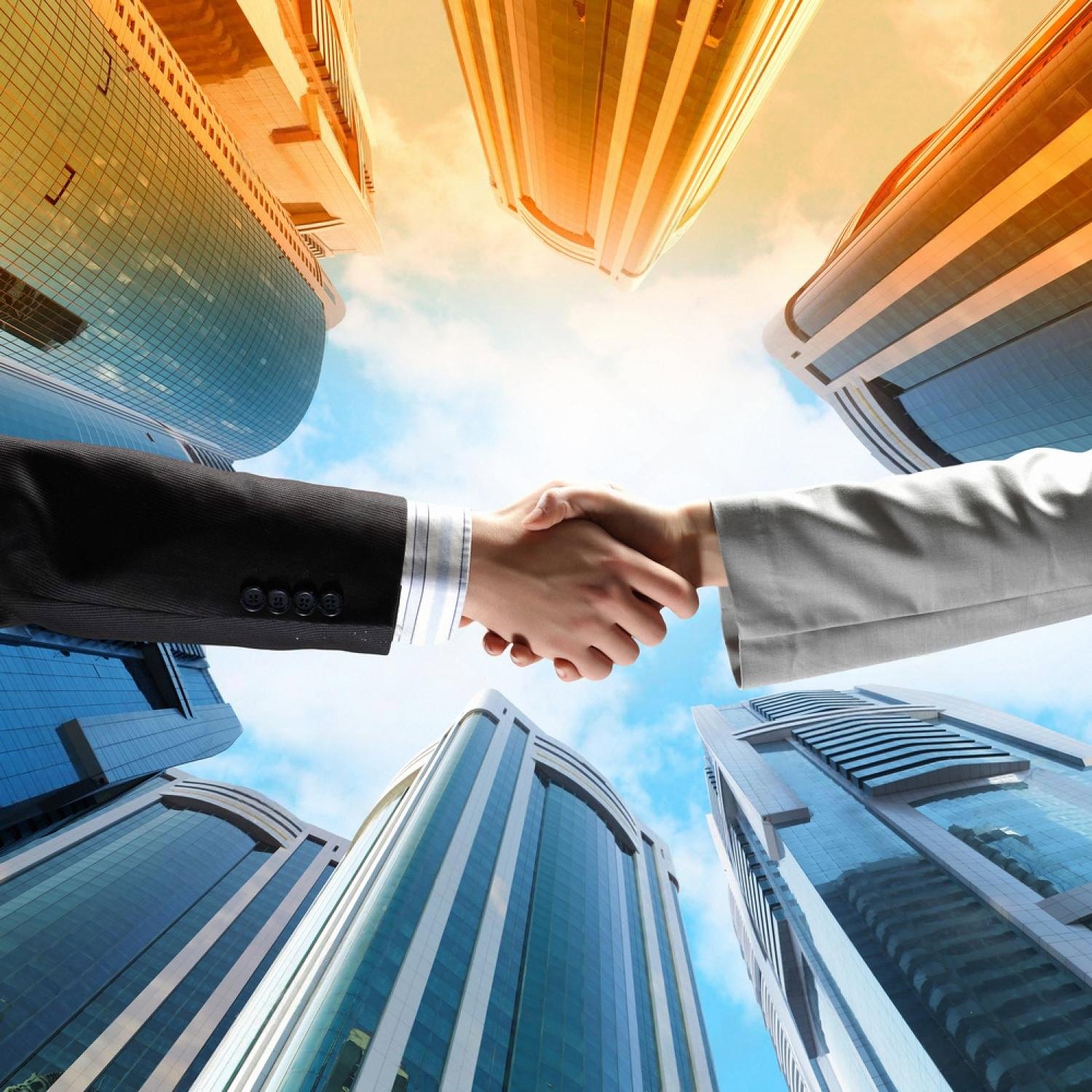 Two business professionals shaking hands between Dubai skyscrapers, symbolising a compliant corporate partnership